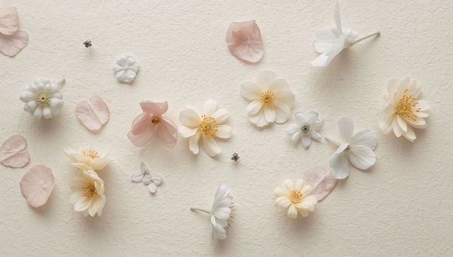 Cream and pale pink floral flatlay on textured paper with soft light and negative space