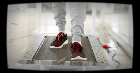 Adult walking on treadmill in grey sweatpants and red sneakers for cardio workout