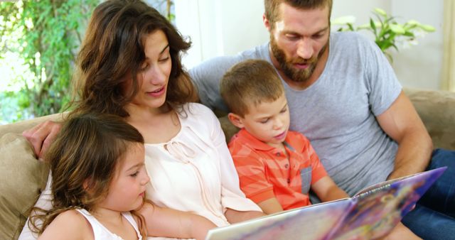 Young family enjoying reading together on couch - Download Free Stock Images Pikwizard.com