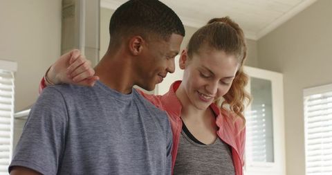Young couple smiling and embracing after home workout in bright modern interior