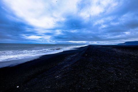 Dramatic volcanic black sand beach under moody sky