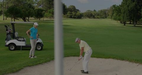 Senior golfer swinging from sand bunker on golf course