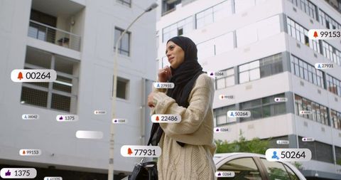 Young muslim woman ending call amid social media notifications floating in urban street