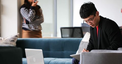 Focused Businessman Writing with Colleague in Background