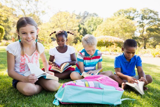 Children sitting on grass in park reading books. Ideal for educational materials, summer camp promotions, diversity and inclusion campaigns, and outdoor learning activities.