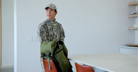 Asian soldier with rucksack in modern indoor setting