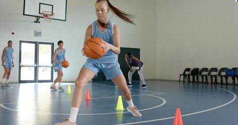 Female Basketball Team Practicing Dribbling Skills in Gym