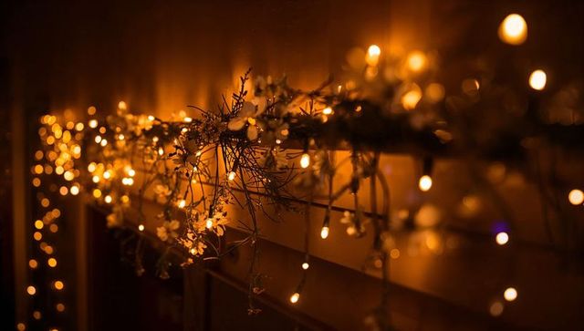 Warm amber garland casting twinkling fairy lights and blossom bokeh along mantel