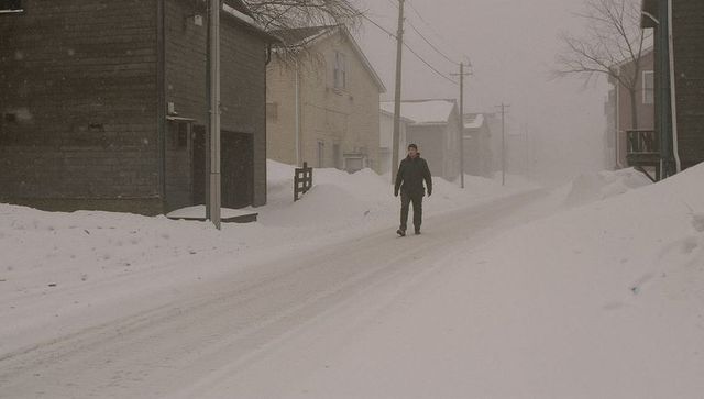 Solitary man walking down snow-packed residential street during heavy winter snowfall