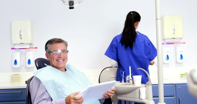 Mid-Aged Man Relaxed in Dental Clinic Holding Dental Records - Download Free Stock Images Pikwizard.com