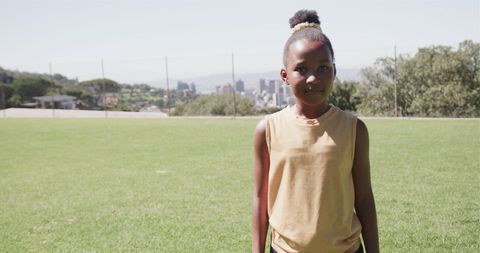 Joyful African American Girl on School Field with Cityscape