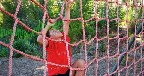 School-age Boy Climbing Net in Outdoor Adventure Course