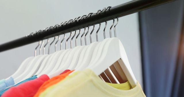 Colorful clothes hang neatly on a rack, showcasing a variety of sizes and styles, with copy space. It's a common sight in retail clothing stores, inviting customers to browse through the selection.