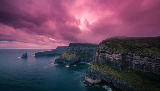 Dramatic Cliffs Under Vibrant Pink Sky at Ocean's Edge