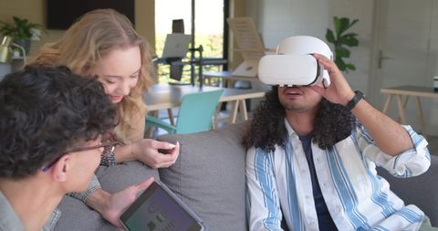 Diverse team testing VR headset and analyzing tablet dashboard in modern co-working lounge