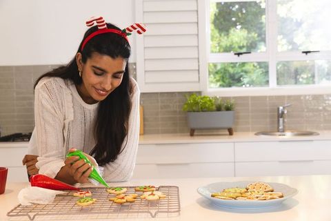 Woman in Kitchen Decorating Christmas Cookies with Festive Icing