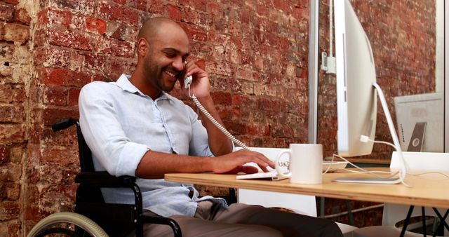 Businessman in Wheelchair Smiling While on Telephone at Office Desk - Download Free Stock Images Pikwizard.com