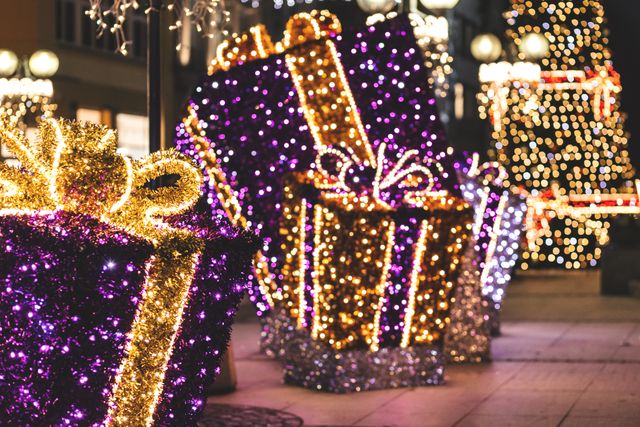 Giant presents wrapped in colorful lights decorated along a city sidewalk offer a festive and cheerful holiday atmosphere. Ideal for marketing holiday events, festive promotions, home decor inspiration, city decorations, and Christmas-themed projects.