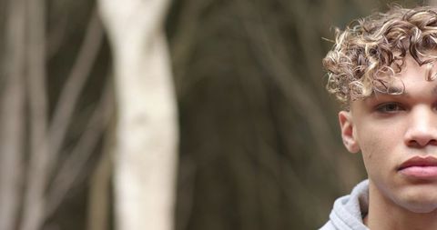 Young Man with Curly Hair in Forest Background