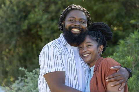 African american couple embracing and smiling outdoors with natural greenery warmth