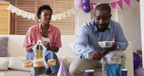 African American couple celebrating birthday at home with cupcakes and blue punch