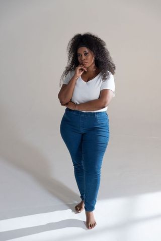 Confident african american woman standing barefoot in minimalist studio, contemplative pose