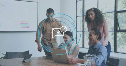 Business team collaborating around laptop and tablet while reviewing charts in modern boardroom