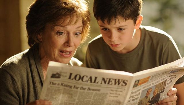 Grandmother and grandson reading local newspaper at home warm intergenerational moment