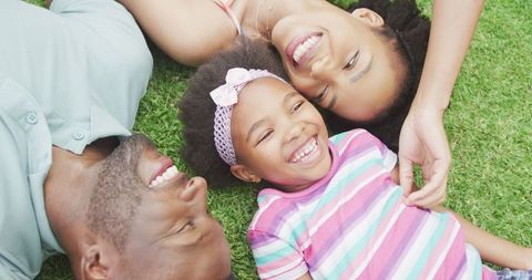 Joyful Family Lying on Grass Enjoying Sunny Day Together
