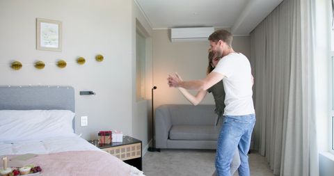 Couple Dancing Joyfully in Cozy Bedroom Celebrating Morning Together