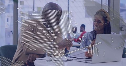 Diverse team collaborating over documents with digital world map overlay