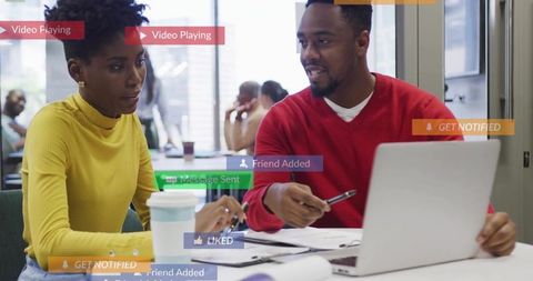 Black professionals collaborating on laptop in coworking lounge with social notifications