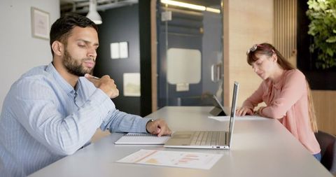 Two Employees Working with Laptops in Modern Office