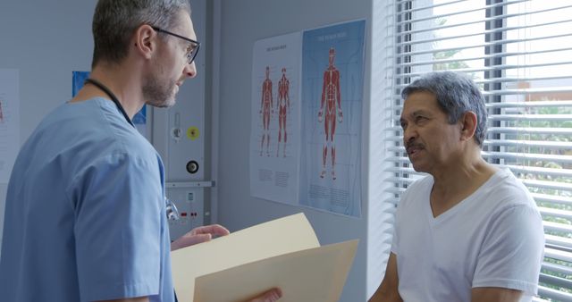 Senior male patient consulting with a doctor in an exam room. Doctor reviewing medical file, discussing diagnosis and treatment options with elderly man wearing a white t-shirt. Suitable for use in health care, medical blogs, patient care materials, and educational resources.