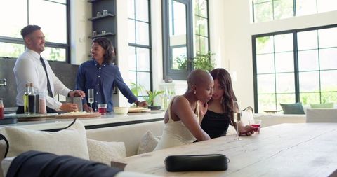 African american women socializing in sunlit modern open-plan kitchen during intimate gathering