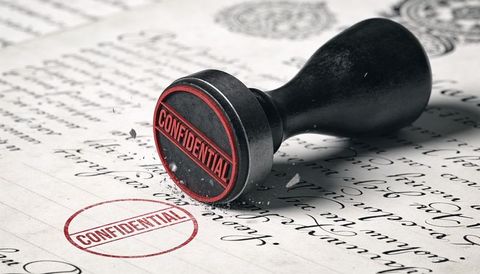Confidential rubber stamp leaving red seal on vintage handwritten document
