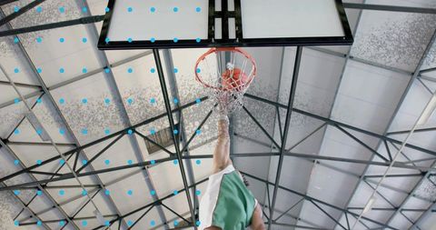 Basketball player dunking ball in gymnasium with dynamic motion
