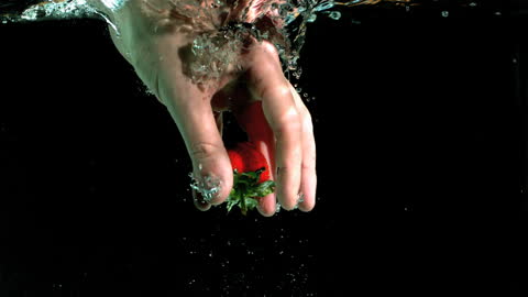 Hand Grabbing Strawberry Underwater in Slow Motion