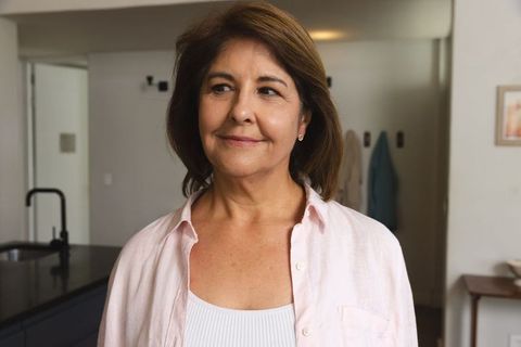 Middle-Aged Woman Adjusting Earrings in Modern Minimalist Kitchen