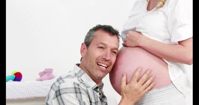 Man listening belly of his pregnant wife at home