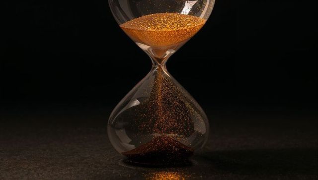 Golden glitter hourglass pouring sparkling sand on dark minimalist crystal timer