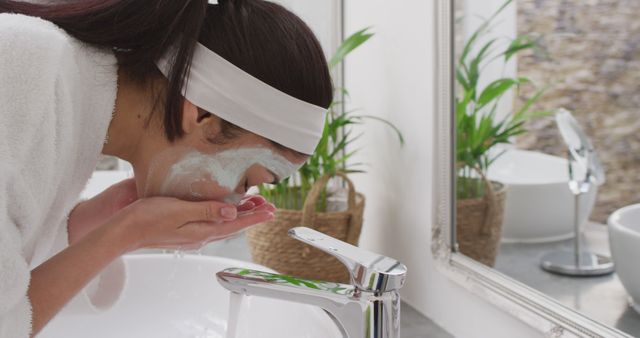 Biracial woman with mask washing face in bathroom. Beauty, health and female spa home concept.
