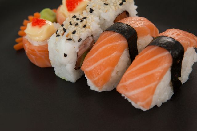 Close-up of maki, uramaki and nigiri sushi served in black plate against white background