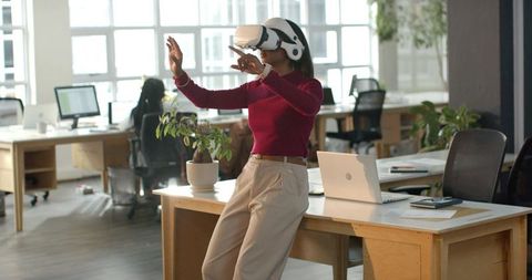 African American woman wearing VR headset exploring virtual collaboration in modern office