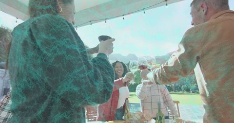 Outdoor wine toasting gathering with red jacket woman leading celebration on covered patio