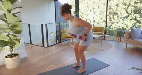 Focused Woman Practicing Weightlifting in Home Living Room