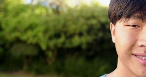 Teenage Boy with Braces Smiling Softly in Garden