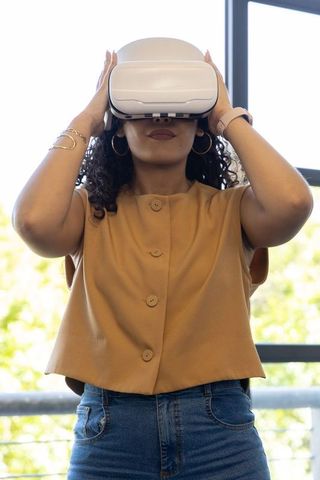 Woman experiencing virtual reality while wearing white vr headset near window