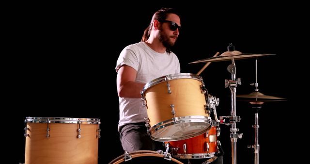 Drummer playing his drum kit on black background
