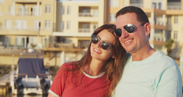 Happy caucasian father and teenage daughter in sunglasses smiling in harbour on a sunny day. Leisure, free time, family, travel and vacations.